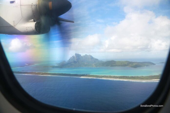 Looking out the window of an airplane and seeing Bora Bora island.