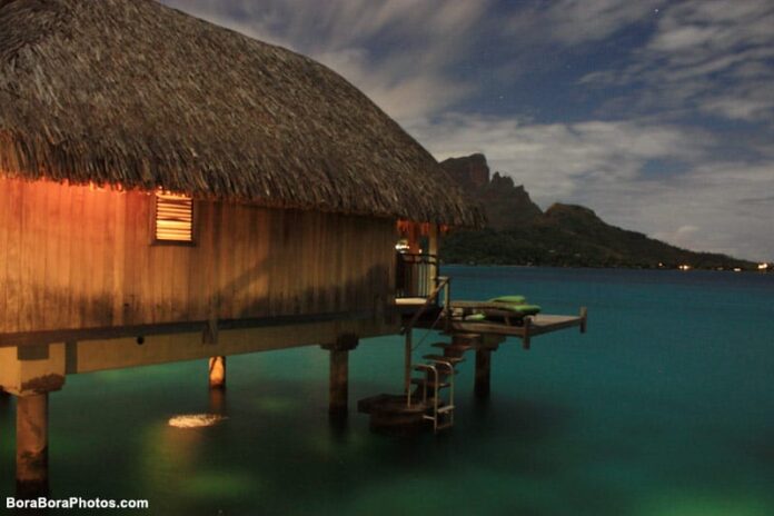 Night time in Bora Bora with over water bungalow with glass floor.