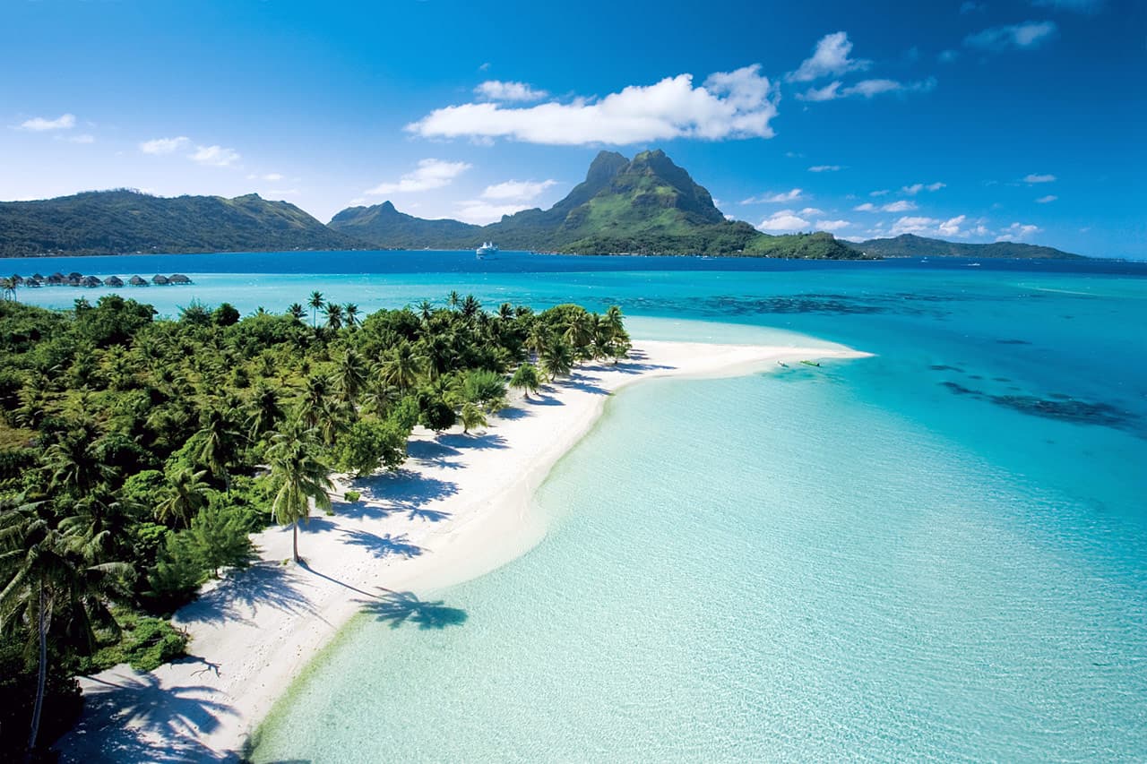 Beautiful white sand beach and colorful blue lagoon in Bora Bora.