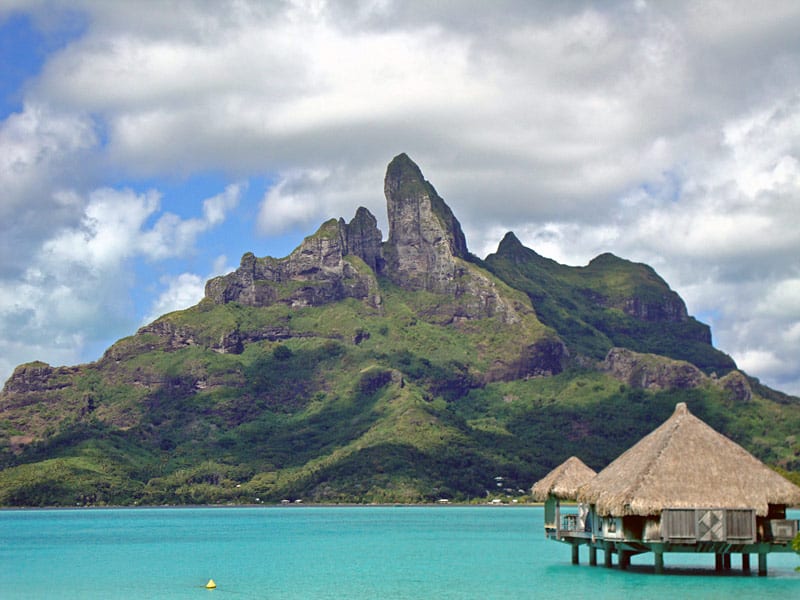 View of Mount Otemanu towering over the Bora Bora lagoon and resort bungalows.