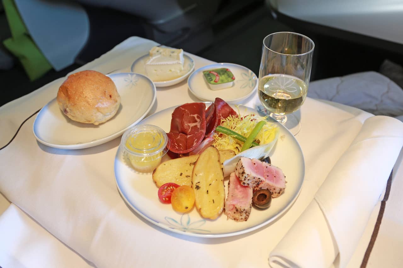 A plate of meat, seafood, and a glass of champagne served in business class.
