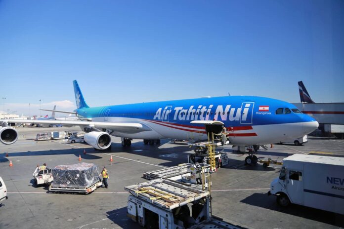 Air Tahiti Nui plane parked at LAX gate waiting to board.