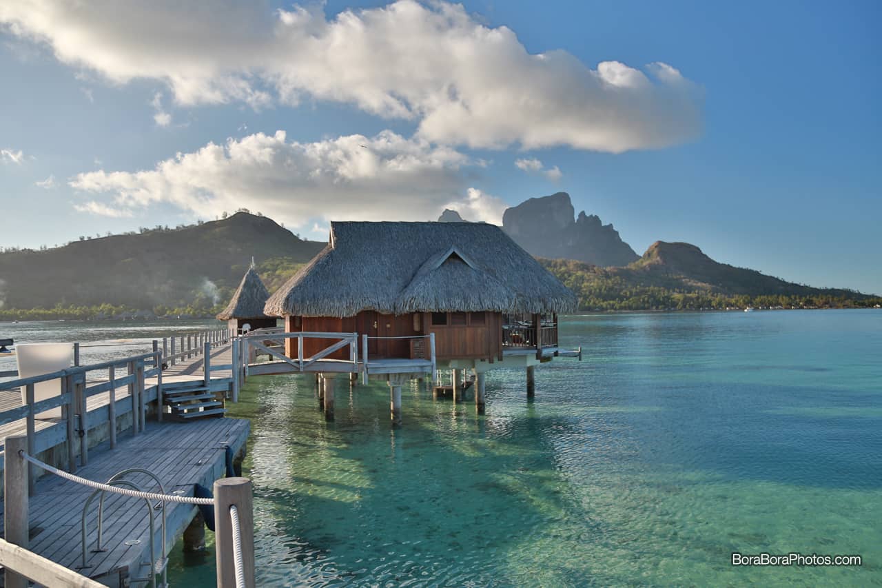 Bora Bora Island overwater bungalow with thatched roof and a glass bottom floor to see the marine life in the lagoon.